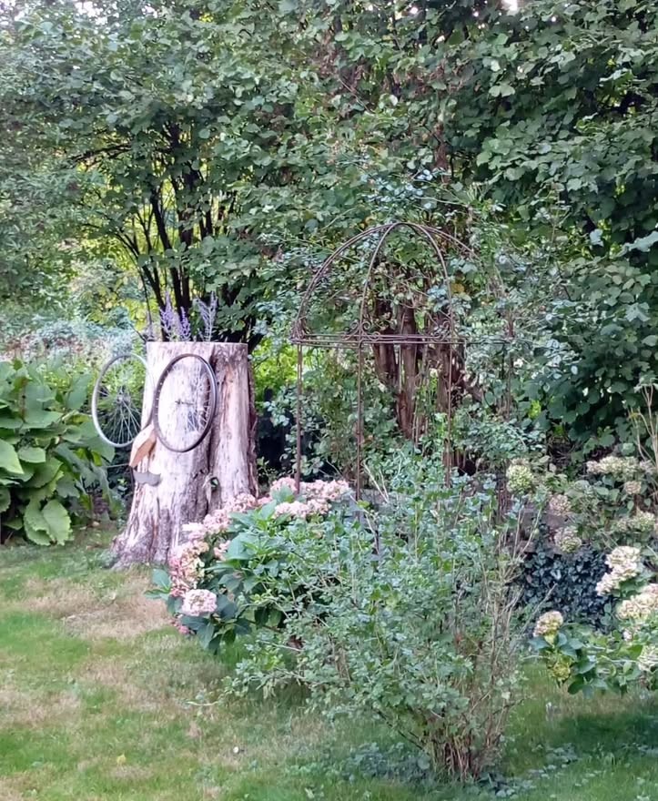 Souche décorée, arche en fer et hortensias dans un jardin privé de Bertrix